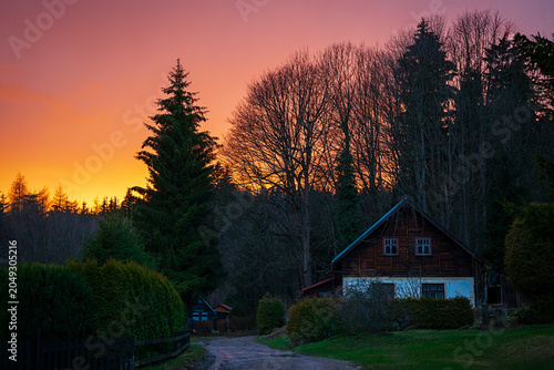 Rural cabin at sunset with colorful sky and forest