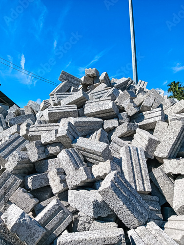 Fotografie Large pile of concrete blocks stacked outdoors at a construction site beneath a vivid blue sky, representing building materials, infrastructure, and development