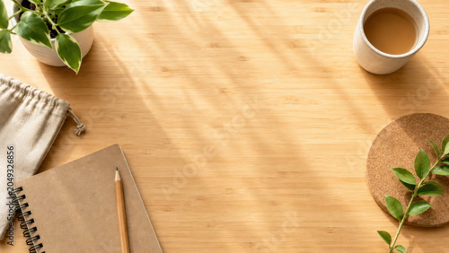 Wood desk coffee cup notebook pencil houseplant workspace Sunlight falls across wood desk with coffee cup, notebook, pencil, houseplant