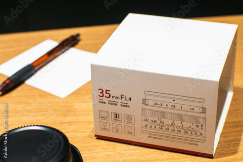 Foto Camera lens box rests on wooden surface