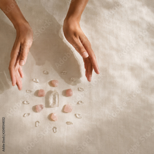 Healing hands surround crystals on linen surface, creating serene atmosphere for meditation and relaxation