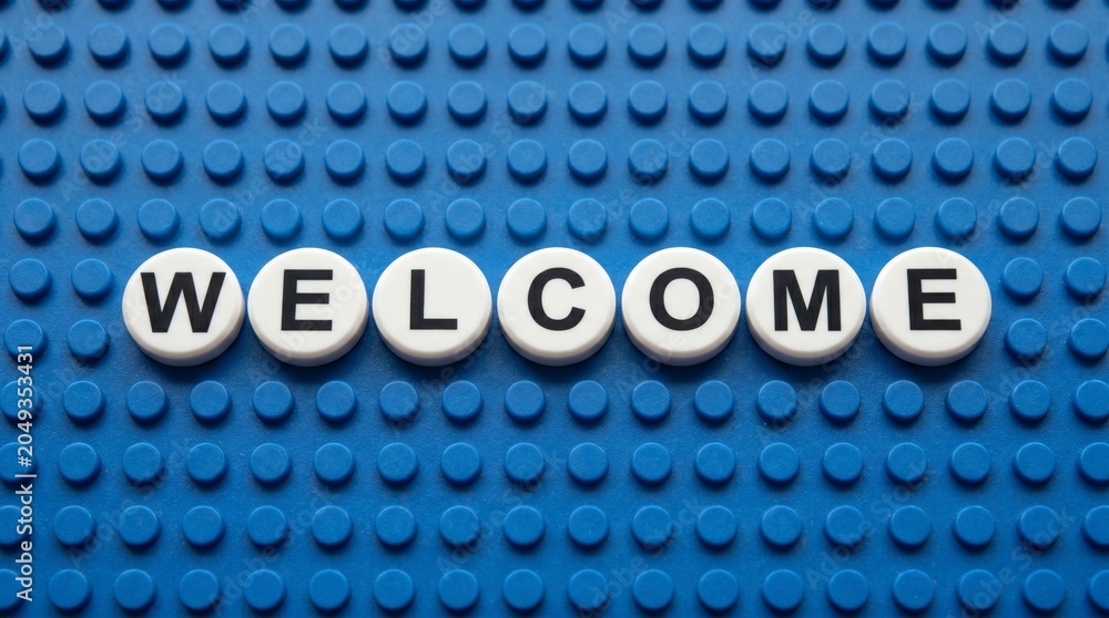 Naklejka premium Creative LEGO‑style welcome sign with white circular tiles on a blue baseplate, bold black letters spelling WELCOME — playful greeting design for hospitality, fun, and introduction visuals