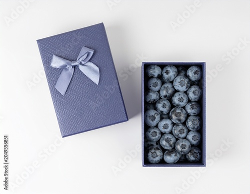 Blueberry fruits filling a gift box on white background