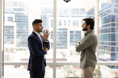 Bilde på lerret Two multiethnic male colleagues engaged in serious conversation, making business