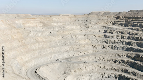 Terraced rock layers of a deep open-pit quarry.