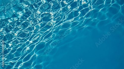 Underwater view of shimmering sunlight on blue pool water surface and caustic patterns