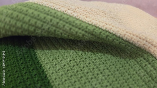 Close-up of folded green crochet fabric with detailed handmade stitches and soft texture, ideal for textile, craft, and home decor themes