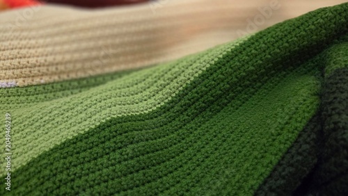 Macro view of a green handmade crochet blanket with detailed stitches and soft folds, emphasizing texture, craftsmanship, and cozy fabric patterns