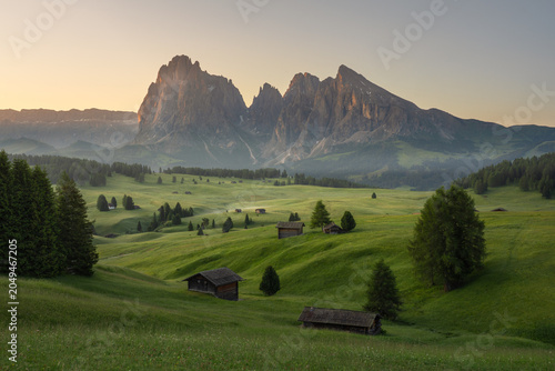 Foto Beautiful sunrise view of Seiser Alm (Alpe di Siusi) with wooden huts, green meadows and dramatic Dolomite mountains in South Tyrol, Italy