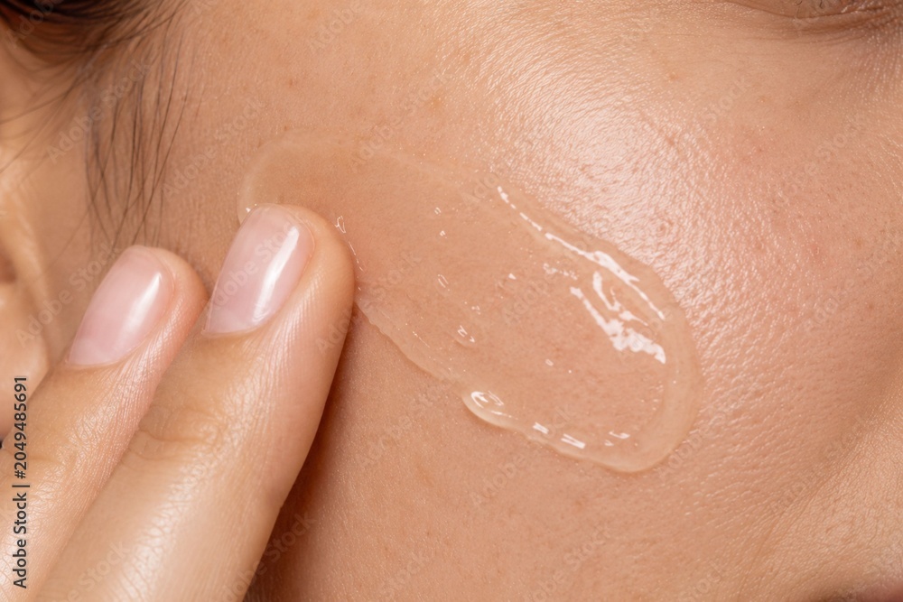 Fototapeta premium Close Up Portrait of Applying Clear Facial Gel to Cheek During Skincare Routine