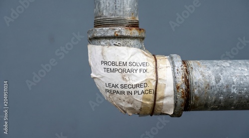 Temporary fix on leaking metal pipe, rusty plumbing joint with problem solved message, industrial water pipe repair with white tape