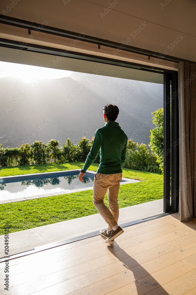 Obraz premium Sun rays are streaming through sliding glass door onto wood floor while pool is reflecting hills