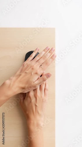 Top View of Two Hands Sharing a Computer Mouse on Wooden Desk.