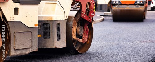 Quadro su tela Heavy Machinery at Work Repairing City Streets With Asphalt Concrete