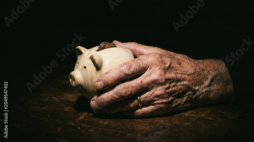Two elderly hands gently cradle a ceramic piggy bank with coins in it. The concept savings, retirement planning, and financial security, targeting finance and elderly care industries. Generative AI.