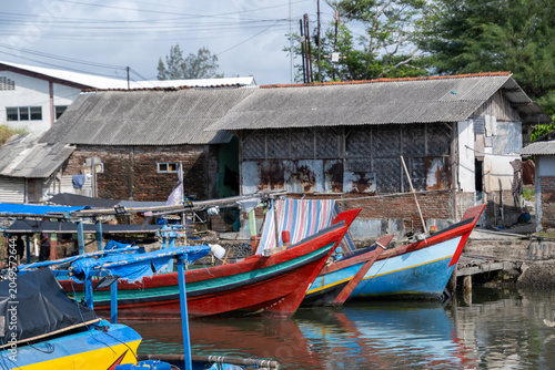 Colorful traditional wooden fishing boats moored along a village harbor in Cilacap, Indonesia.