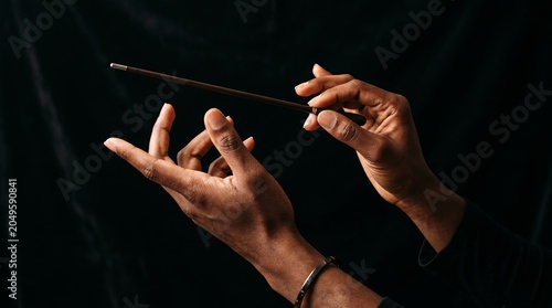 A detailed view of a person's hands delicately holding a conductor's baton. Concept of music, art, performance, elegance, and creativity for stock photography usage. Generative AI.