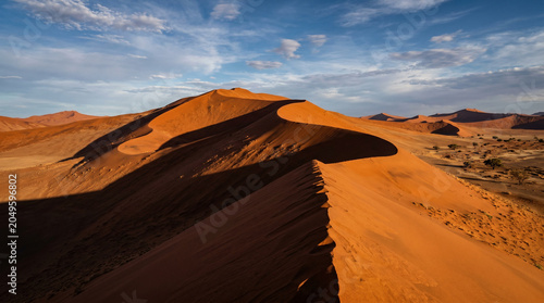 Canvas Print Dramatic, towering dunes of deep orange and red, with shadows creating dynamic patterns