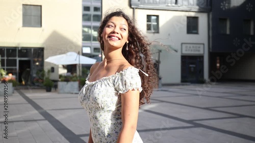 Beautiful young girl walking on a pedestrian street on a summer day, looking over her shoulder