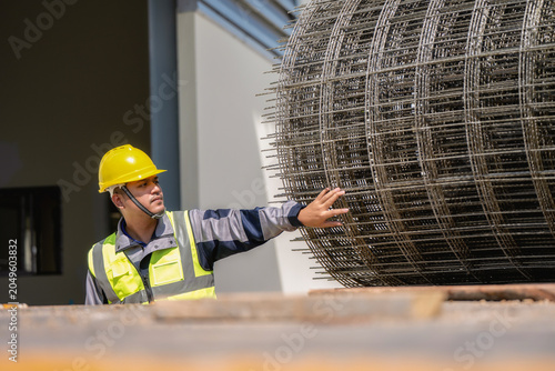 Asian workers inspect the wire mesh on the truck. ,  Construction worker in a yellow hard hat
