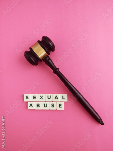 Gavel and sexual abuse words on pink background
