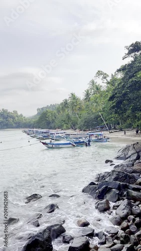 Traditional Outrigger Boats Anchored at Tropical Beach with Palm Trees and Rocky Coastline