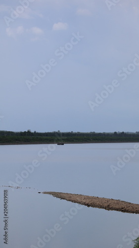 The image depicts a calm body of water with a smooth surface reflecting the sky above