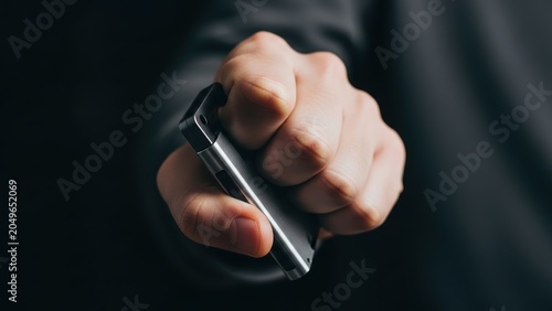 Hand tightly gripping silver hardware cryptocurrency digital wallet device.