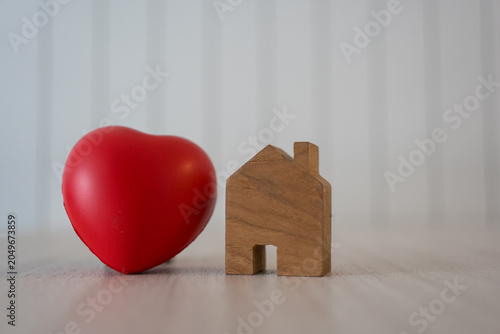 Wooden house and a heart shaped on table for design represent love and Valentine's Day.