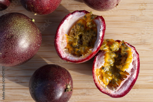 Картината върху платно High-angle shot of ripe purple passion fruit cut in half on a light wooden cutti