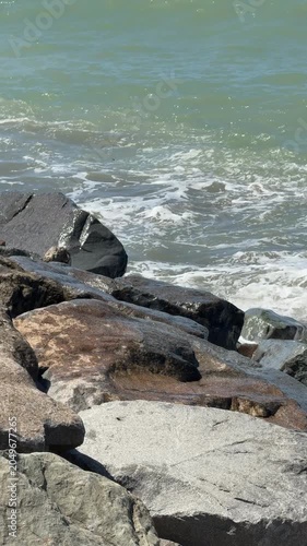 Rocky shoreline with waves crashing against stones, suitable for backgrounds or nature themes