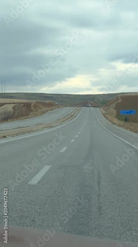 Turkish road stretching through countryside under cloudy sky, showcasing wide open landscape