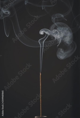 Burning Incense Stick with Swirling Smoke on Dark Background