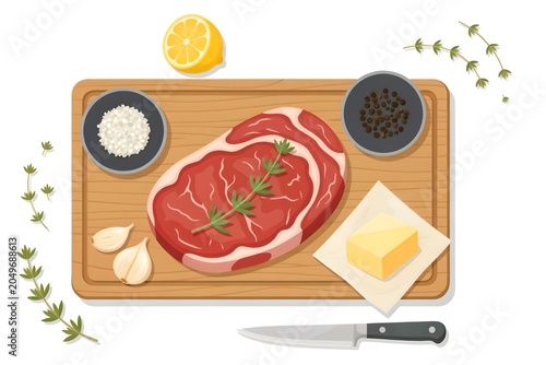 A top-down view of a raw ribeye steak prepared with salt, pepper, garlic, lemon, butter, and herbs for cooking