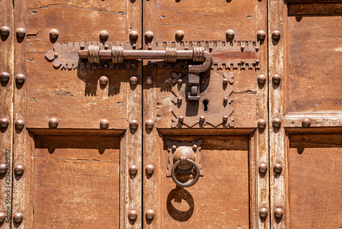 Picturesque metal latch on door of historic portal, detail of medieval architecture in old town, Gubbio, Umbria, Italy