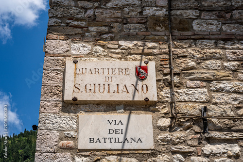 Street plaque of San Giuliano historic district, mounted along Via Battilana in medieval old town, Gubbio, Umbria, Italy