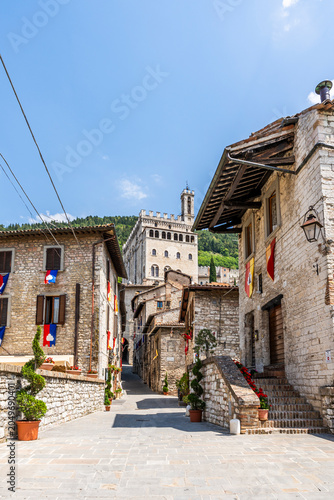 Picturesque view of medieval historic center along Via Piccardi, Palazzo dei Consoli visible in background, Gubbio, Umbria, Italy