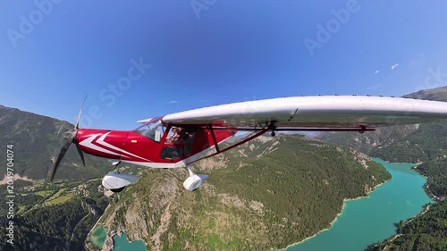 aerial footage, dynamic selfportrait of light airplane flying over turquoise lake in provence under blue sky and beautiful wthite clouds