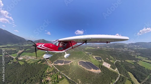 aerial footage, dynamic selfportrait of light airplane flying over provencal landscape and solar farm under blue sky and beautiful wthite clouds