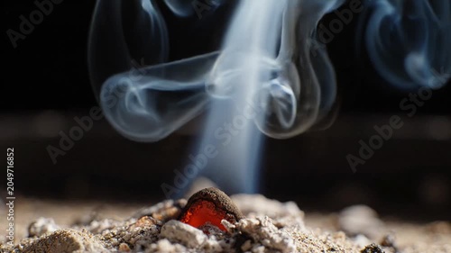 Macro closeup of burning incense cone with white smoke rising, creating a serene and meditative atmosphere