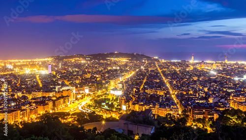 Vast cityscape illuminated at dusk with glowing lights and dramatic twilight sky, urban sprawl and distant hills