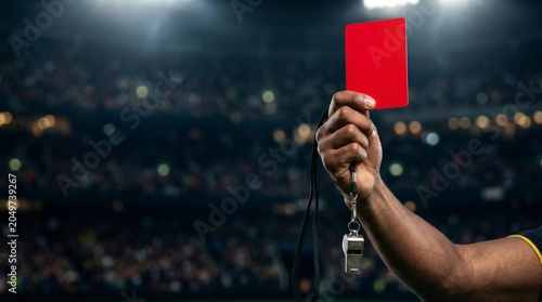 Soccer referee hand holding red card penalty during football match in stadium night lights close up