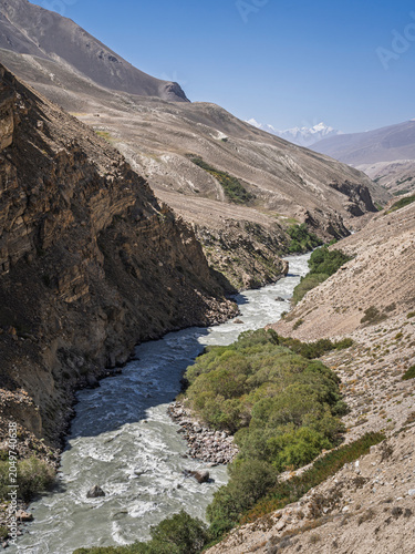 Vertical landscape view of Pamir river valley in high altitude mountain desert with Hindu Kush in background, Ishkashim, Gorno-Badakhshan, Tajikistan