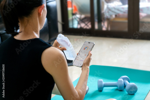 Woman taking a break during home fitness workout checking phone app