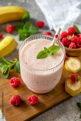 Pink raspberries and banana fruit smoothie or milk protein shake on stone tabletop. Yogurt cocktail, natural detox. Liquid ice cream.