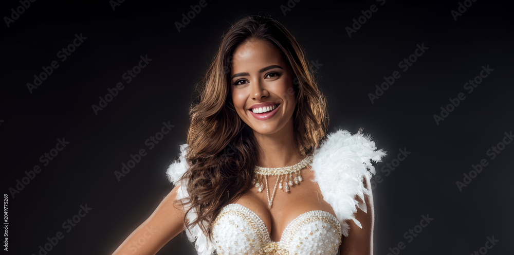 Obraz premium A woman in a white lace dress stands with large feather wings on a dark background. The front facing portrait is centered.