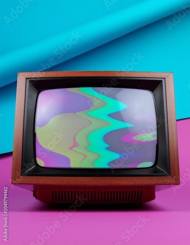 Vintage television with colorful abstract display on pink surface.