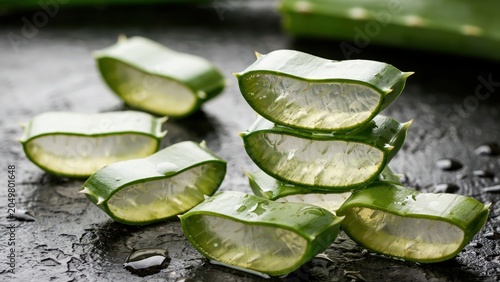 Close up of fresh aloe vera leaf slices showing clear gel texture on a dark wet surface