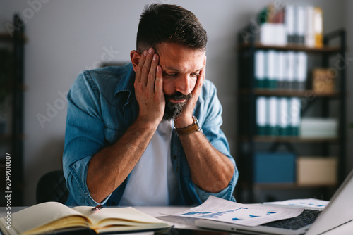 Foto Stressed businessman suffering from headache and occupational burnout