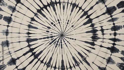 Abstract tiedye pattern with a radial sunburst design in black and offwhite, featuring organic inklike streaks and concentric circular motifs in a symmetrical composition